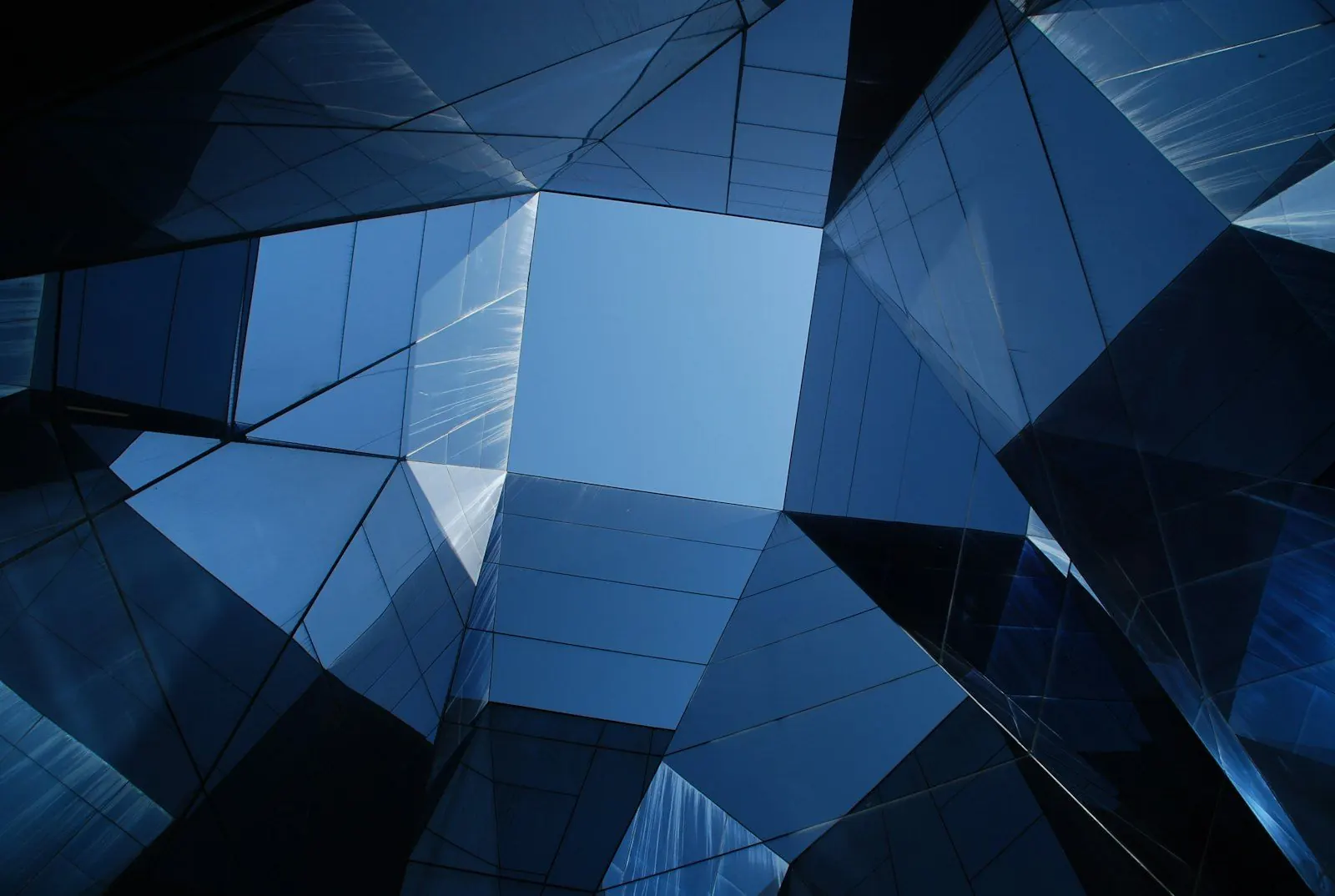 Angular glass facade reflecting a blue sky