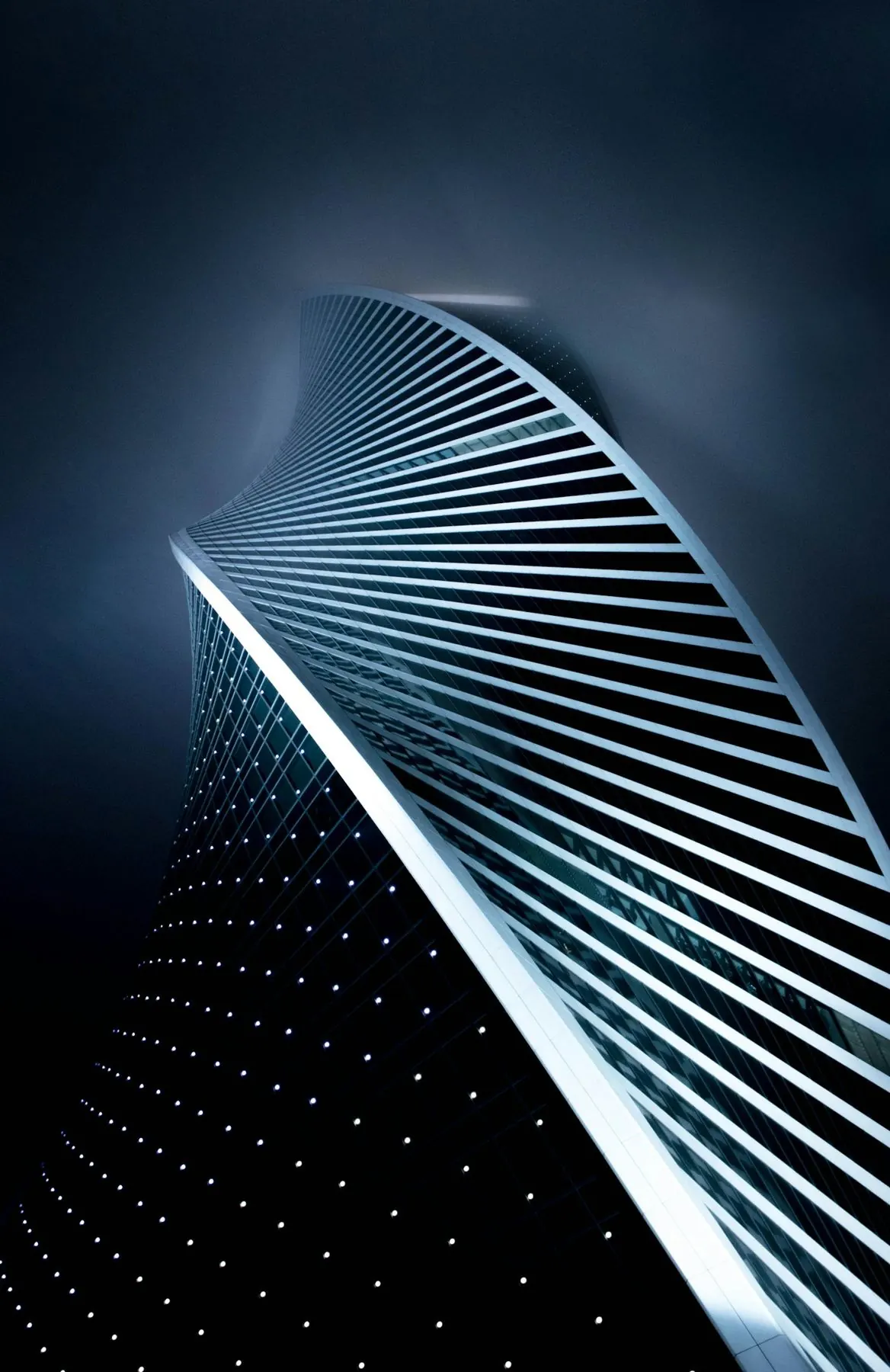 Twisting modern skyscraper lit against a dark sky